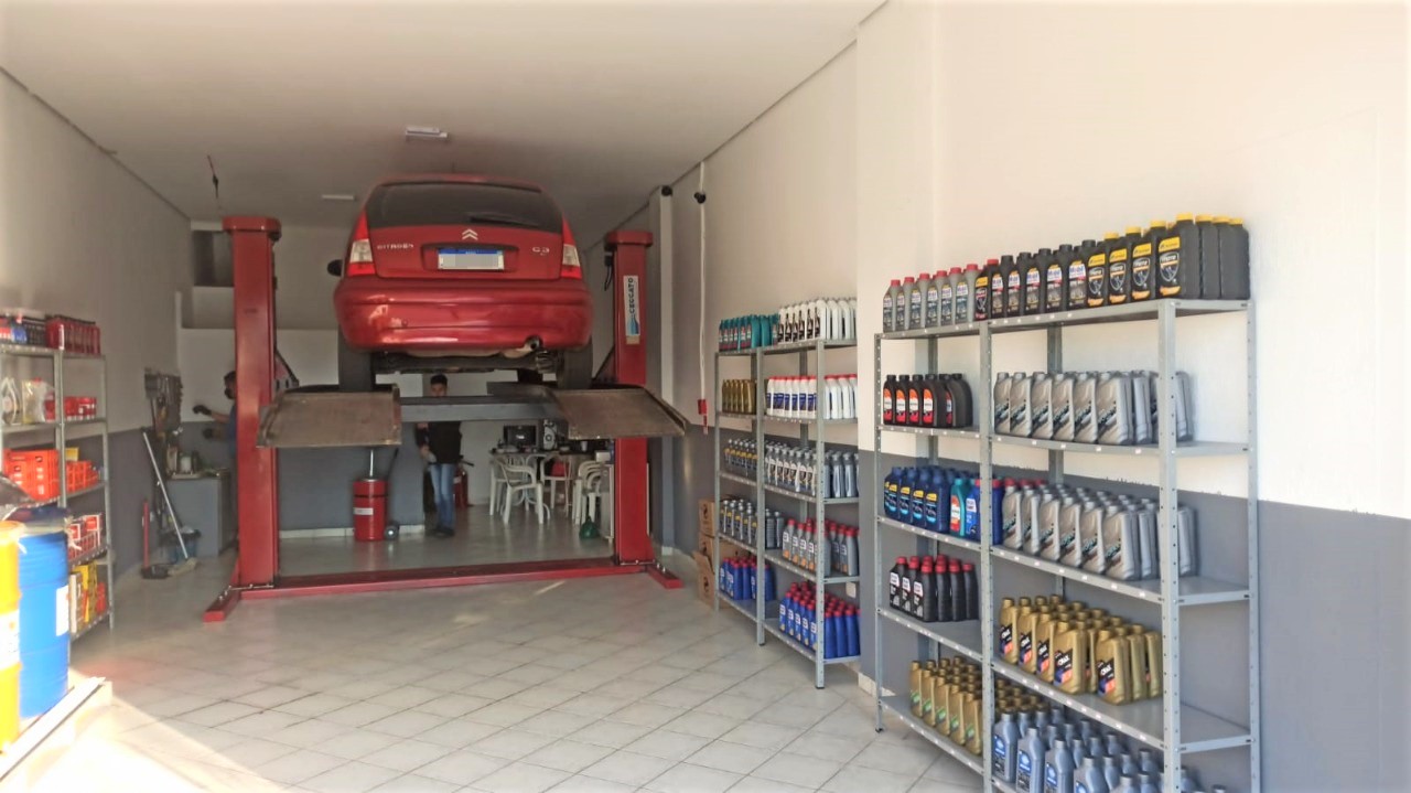 Interior da Troca de Óleo Maracanã em Praia Grande, com veículo no elevador e prateleiras de lubrificantes
